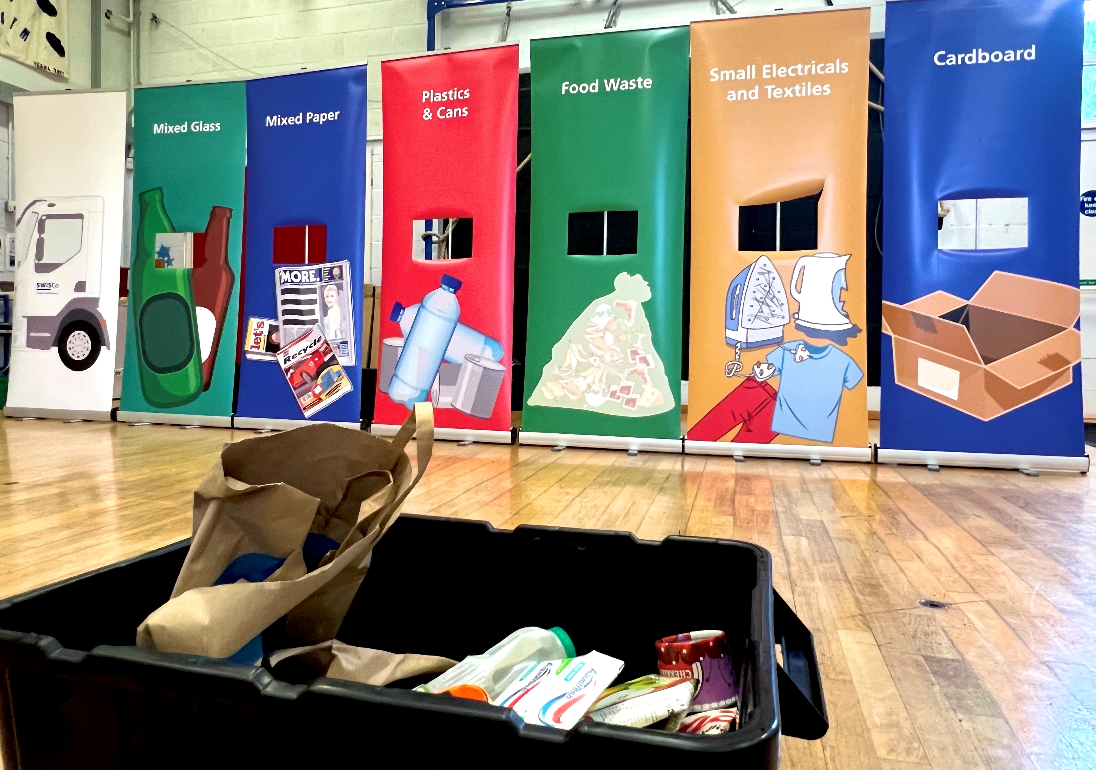 A school activity, showing pull up banners making the compartments of a recycling vehicle