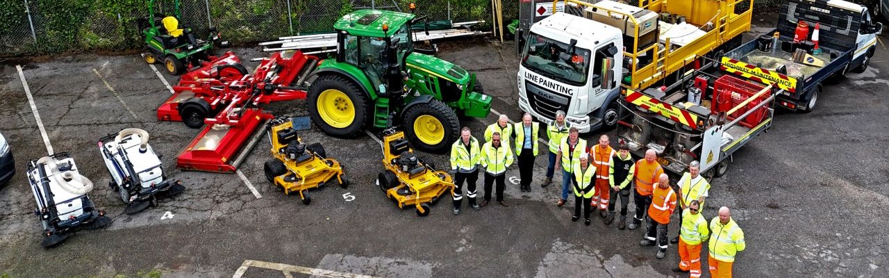 Aerial view of a group of SWISCo staff, stood next to fleet vehicles