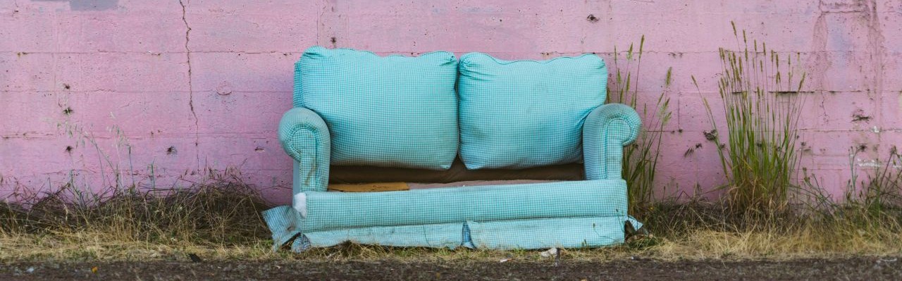 a pale green soft dumped next to a pink wall